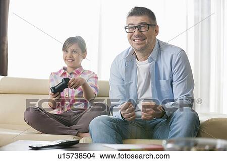 Happy father and daughter enjoying video game in living room View Large Photo Image Picture - Happy father and daughter enjoying video game in living room. Fotosearch