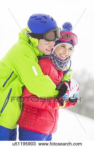 Stock Image - Happy loving man hugging woman in snow. Fotosearch