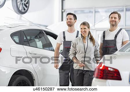 Happy maintenance engineers looking away in automobile repair shop View Large Photo Image Stock Photo - Happy maintenance engineers looking away in automobile repair shop. Fotosearch