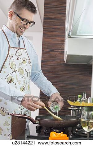 Happy man adding white wine to saucepan while cooking in kitchen View Large Photo Image Stock Image - Happy man adding white wine to saucepan while cooking in kitchen. Fotosearch