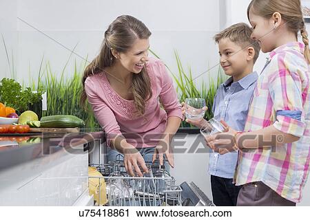 Happy mother and children placing glasses in dishwasher View Large Photo Image Stock Image - Happy mother and children placing glasses in dishwasher. Fotosearch