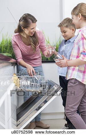 Happy mother and children placing glasses in dishwasher View Large Photo Image Stock Photo - Happy mother and children placing glasses in dishwasher. Fotosearch