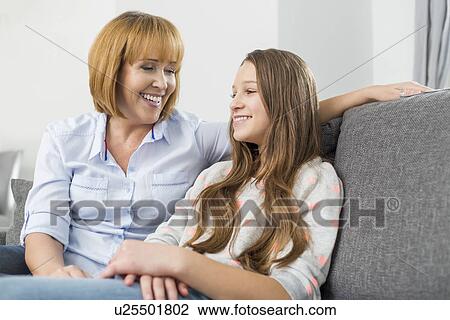 Stock Image - Happy mother and daughter relaxing on sofa at home. Fotosearch