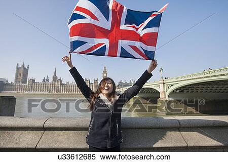 Happy woman holding British flag while standing against Big Ben at London, England, UK View Large Photo Image Stock Photography - Happy woman holding British flag while standing against Big Ben at London, England, UK. Fotosearch