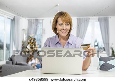 Happy woman shopping online at home during Christmas View Large Photo Image Stock Photo - Happy woman shopping online at home during Christmas. Fotosearch