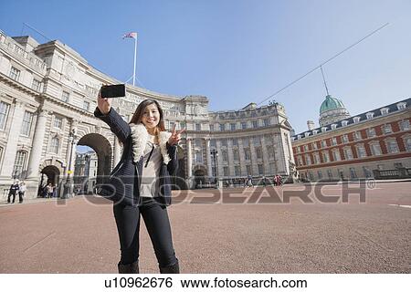 Stock Photograph - Happy woman taking self portrait against Admiralty Arch in London, England, UK. Fotosearch