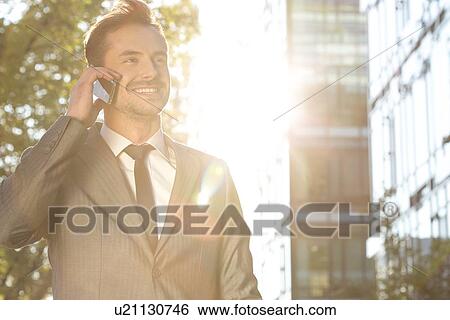 Happy young businessman using cell phone outdoors View Large Photo Image Stock Photograph - Happy young businessman using cell phone outdoors. Fotosearch