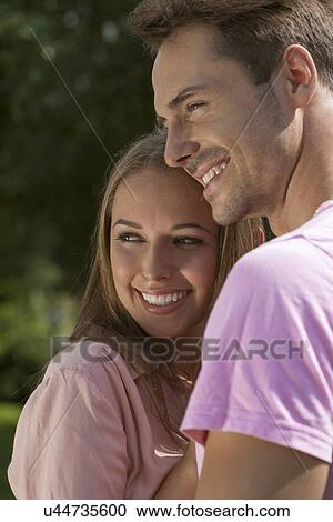 Happy young couple embracing in park View Large Photo Image Stock Image - Happy young couple embracing in park. Fotosearch