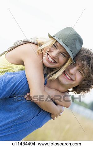 Happy young couple enjoying in field View Large Photo Image Picture - Happy young couple enjoying in field. Fotosearch