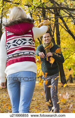 Happy young couple playing with autumn leaves in park View Large Photo Image Stock Photography - Happy young couple playing with autumn leaves in park. Fotosearch