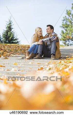Happy young couple sitting on steps in park View Large Photo Image Stock Image - Happy young couple sitting on steps in park. Fotosearch