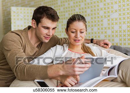 Happy young couple using tablet PC at home View Large Photo Image Stock Photography - Happy young couple using tablet PC at home. Fotosearch