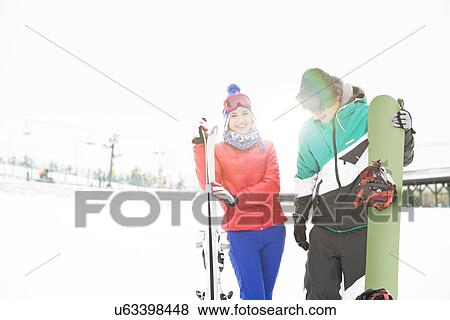Happy young couple with snowboard and skis in snow View Large Photo Image Stock Photo - Happy young couple with snowboard and skis in snow. Fotosearch