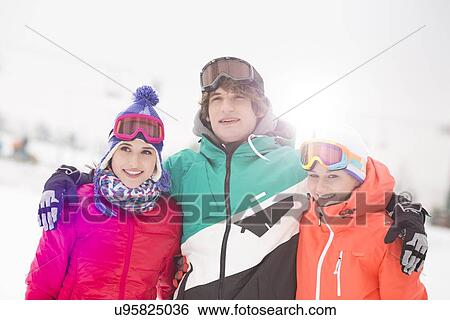 Happy young man with female friends standing arm around in snow View Large Photo Image Stock Photograph - Happy young man with female friends standing arm around in snow. Fotosearch