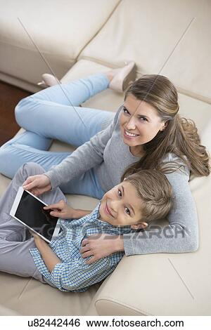 High angle portrait of mother and son with tablet PC sitting on sofa View Large Photo Image Stock Photograph - High angle portrait of mother and son with tablet PC sitting on sofa. Fotosearch