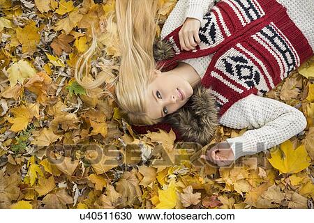 High angle portrait of young woman lying on autumn leaves in park View Large Photo Image Stock Image - High angle portrait of young woman lying on autumn leaves in park. Fotosearch