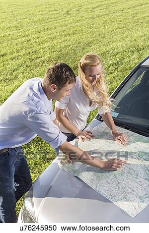High angle view of couple reading map on car hood during road trip View Large Photo Image Stock Image - High angle view of couple reading map on car hood during road trip. Fotosearch