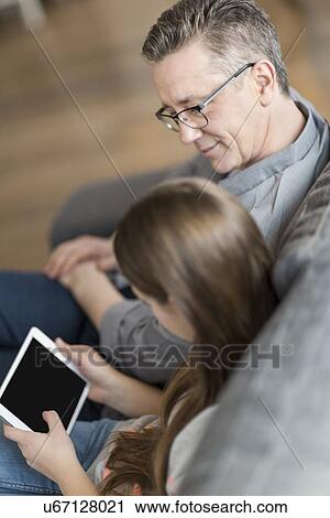 High angle view of father and daughter using digital tablet at home View Large Photo Image Stock Image - High angle view of father and daughter using digital tablet at home. Fotosearch
