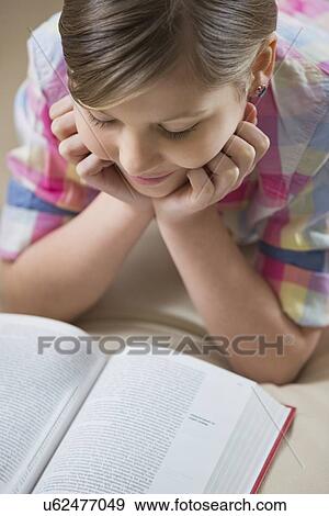 High angle view of girl reading book at home View Large Photo Image Stock Photo - High angle view of girl reading book at home. Fotosearch