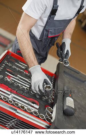 Stock Photo - High angle view of male mechanic arranging tools in drawer at car repair shop. Fotosearch