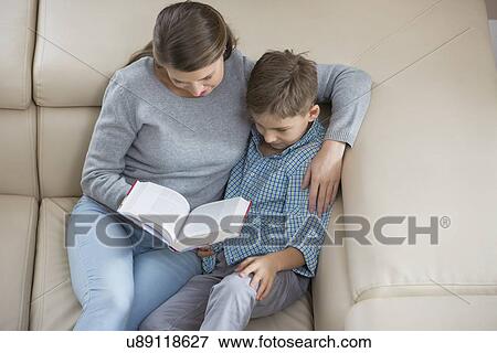 High angle view of mother and son reading book on sofa View Large Photo Image Stock Photo - High angle view of mother and son reading book on sofa. Fotosearch