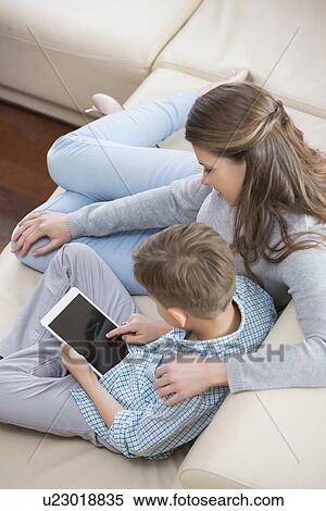 High angle view of mother and son using tablet PC on sofa View Large Photo Image Stock Photography - High angle view of mother and son using tablet PC on sofa. Fotosearch