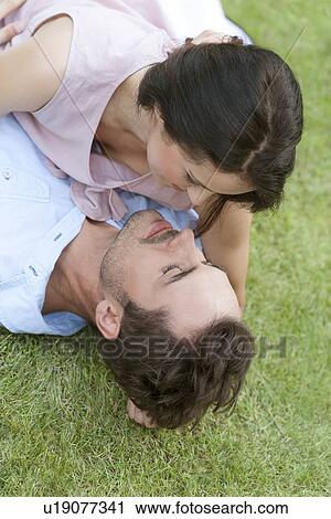 High angle view of romantic young couple lying together in park View Large Photo Image Stock Image - High angle view of romantic young couple lying together in park. Fotosearch