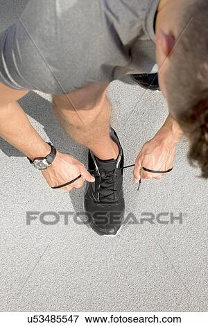 High angle view of sporty man tying shoelace on street View Large Photo Image Stock Photo - High angle view of sporty man tying shoelace on street. Fotosearch