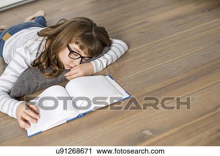 Stock Image - High angle view of teenage girl sleeping while studying on floor. Fotosearch