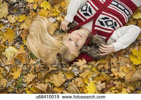 High angle view of thoughtful young woman lying on autumn leaves in park View Large Photo Image Stock Photo - High angle view of thoughtful young woman lying on autumn leaves in park. Fotosearch