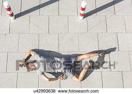 High angle view of tired sporty man lying on sidewalk View Large Photo Image Stock Photo - High angle view of tired sporty man lying on sidewalk. Fotosearch