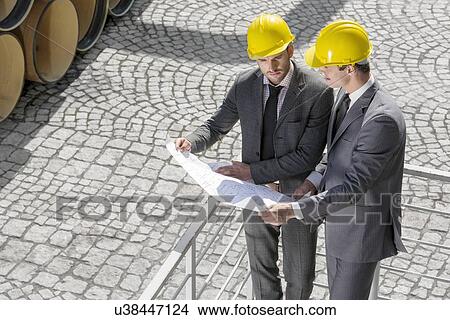 High angle view of young male architects examining blueprint by railings View Large Photo Image Picture - High angle view of young male architects examining blueprint by railings. Fotosearch