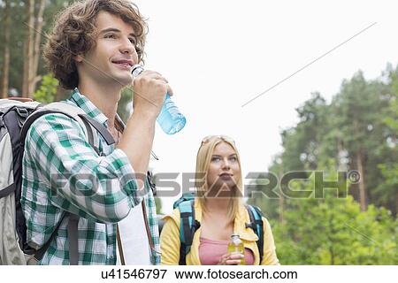 Hiking couple drinking energy drinks in forest View Large Photo Image Stock Photo - Hiking couple drinking energy drinks in forest. Fotosearch
