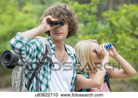 Hiking couple using binoculars in forest View Large Photo Image Stock Image - Hiking couple using binoculars in forest. Fotosearch