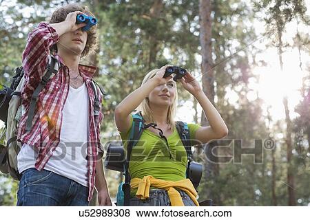 Hiking couple using binoculars in forest View Large Photo Image Stock Photo - Hiking couple using binoculars in forest. Fotosearch