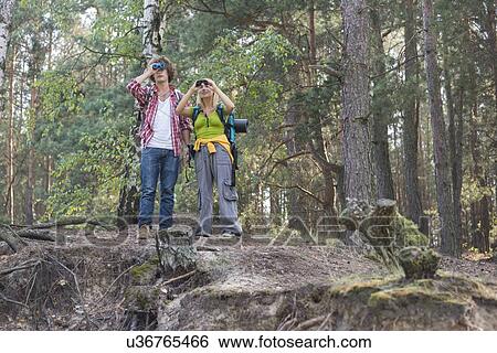 Hiking couple using binoculars in forest View Large Photo Image Stock Photograph - Hiking couple using binoculars in forest. Fotosearch