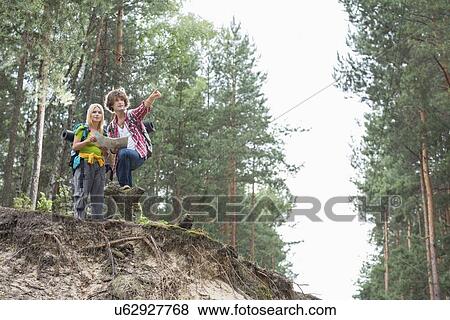 Stock Photo - Hiking couple with map discussing over direction in forest. Fotosearch