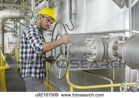 Stock Photo - Industrial worker turning large valve. Fotosearch