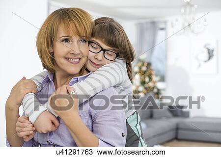 Stock Image - Loving daughter embracing mother at home. Fotosearch