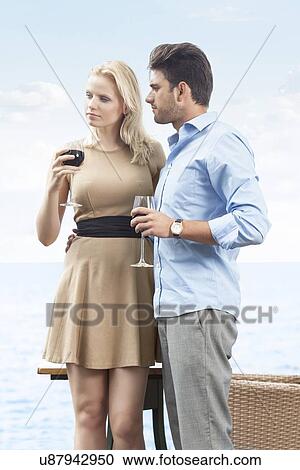 Loving young couple having red wine at outdoor restaurant by lake View Large Photo Image Stock Image - Loving young couple having red wine at outdoor restaurant by lake. Fotosearch