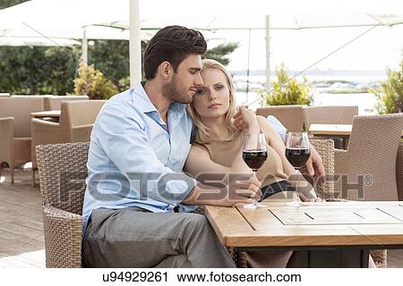 Stock Image - Loving young couple having red wine at outdoor restaurant. Fotosearch