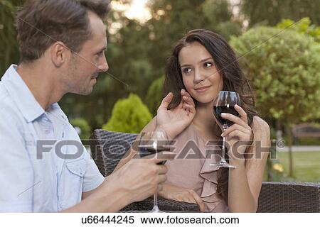 Loving young couple holding wine glasses in park View Large Photo Image Stock Photography - Loving young couple holding wine glasses in park. Fotosearch