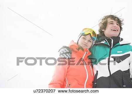 Loving young couple in warm clothing against clear sky View Large Photo Image Stock Photo - Loving young couple in warm clothing against clear sky. Fotosearch