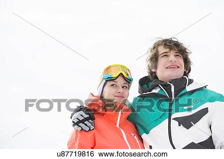 Stock Photograph - Loving young couple in warm clothing against clear sky. Fotosearch
