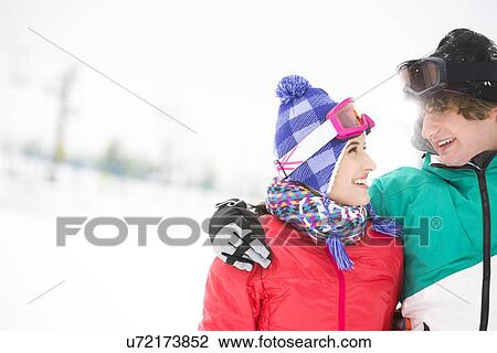 Stock Image - Loving young couple looking at each other in snow. Fotosearch