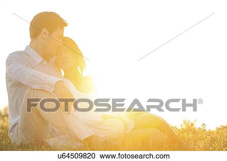 Loving young couple sitting on grass at park against clear sky View Large Photo Image Stock Image - Loving young couple sitting on grass at park against clear sky. Fotosearch