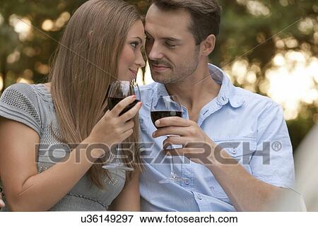 Loving young couple toasting red wine in park View Large Photo Image Stock Photo - Loving young couple toasting red wine in park. Fotosearch