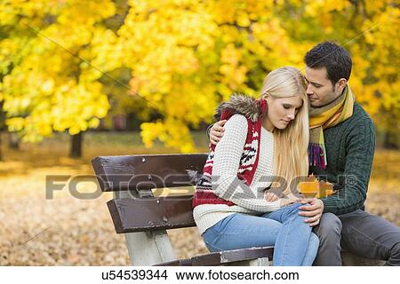 Loving young man hugging shy woman on park bench during autumn View Large Photo Image Picture - Loving young man hugging shy woman on park bench during autumn. Fotosearch