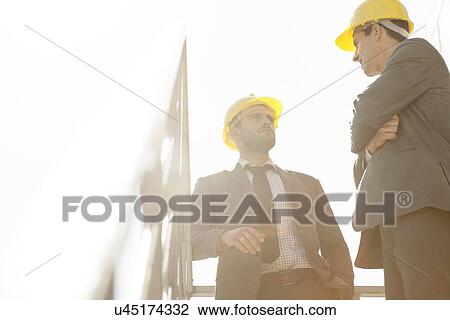 Low angle view of young male architect having discussion on stairway against clear sky View Large Photo Image Stock Image - Low angle view of young male architect having discussion on stairway against clear sky. Fotosearch
