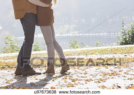 Low section of couple standing in park during autumn View Large Photo Image Stock Photo - Low section of couple standing in park during autumn. Fotosearch